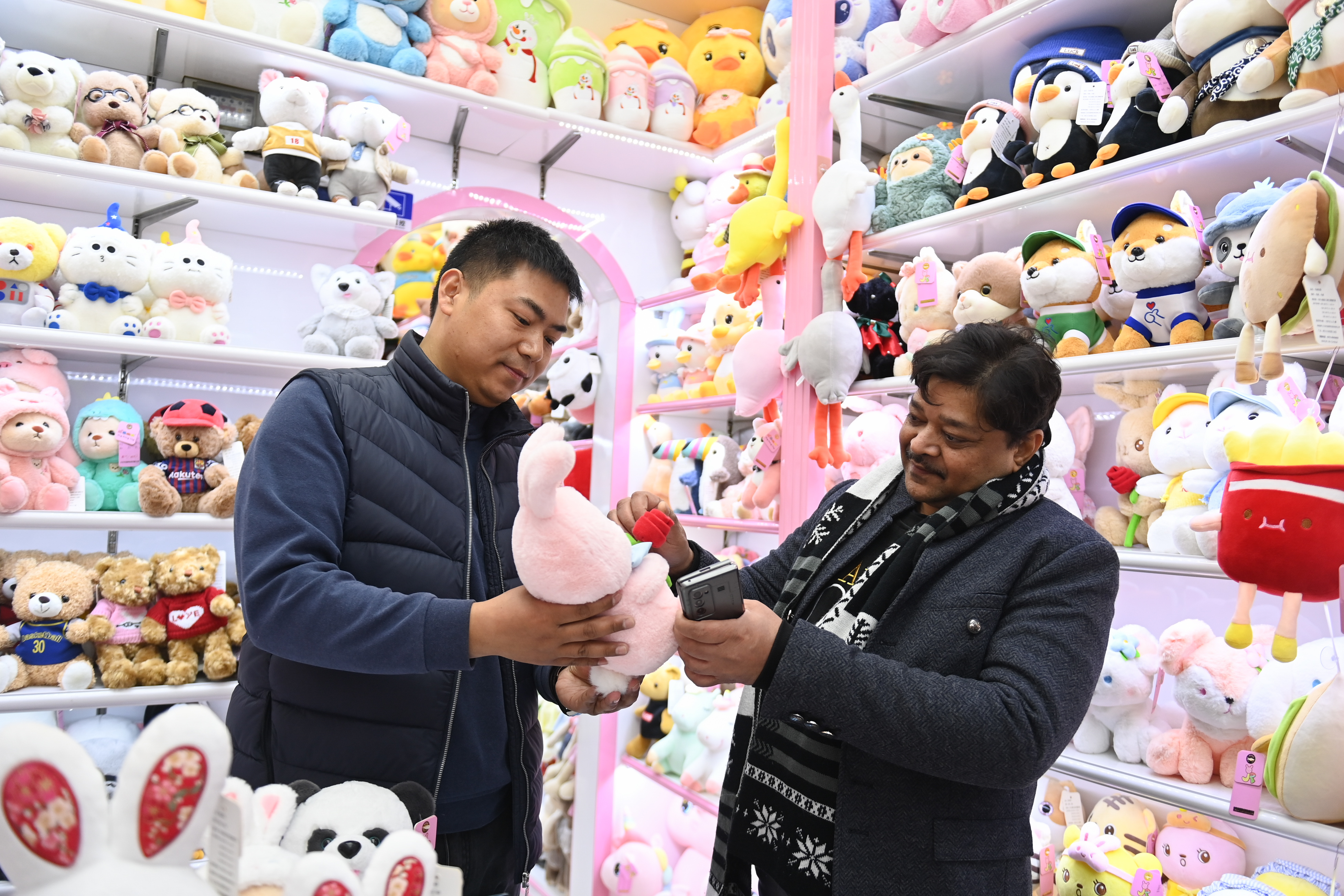 2023年2月2日，來自印度的客商（右）在義烏國際商貿(mào)城的一家玩具店鋪內(nèi)選購。